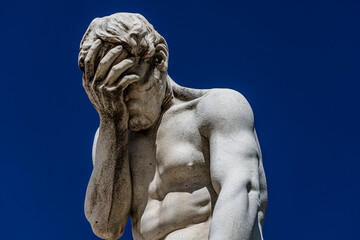 Paris, France - 15 September 2022: Sad and frustrated man face palm white sculpture on the blue clear sky background