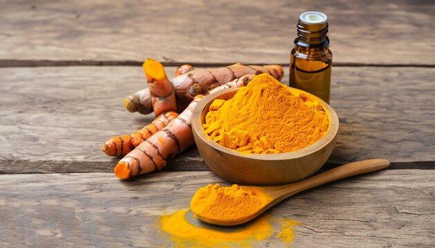 Tumeric (curcumin, curcuma longa Linn) powder in wooden bowl and spoon with root and bottle of turmeric essential oil extracted isolated on old wood table background. Beauty and spa concept.