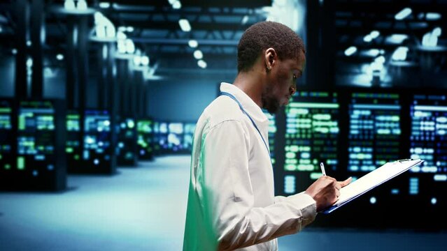 Worker taking note of supercomputers performing data backups and providing centralized storage. Mechanic offering technical support in Uninterruptible Power Supply ensuring operational continuity