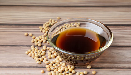 Soy sauce in glass bowl with soybeans isolated on wooden table background.
