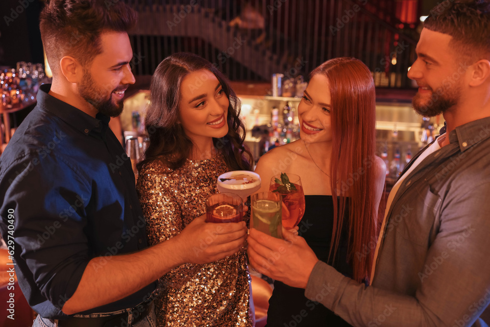 Sticker happy friends clinking glasses with fresh cocktails in bar