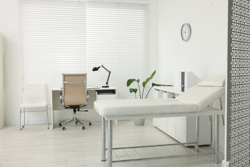 Modern medical office with doctor's workplace and examination table in clinic