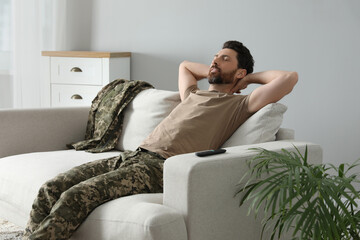 Soldier napping on soft sofa in living room. Military service