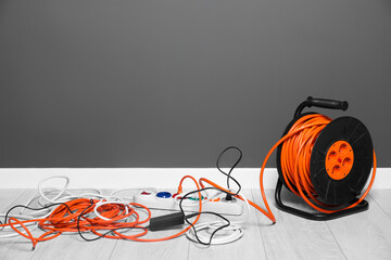 Extension cord reel plugged into power strip indoors, space for text. Electrician's equipment