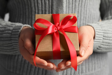 Woman holding gift box with red bow, closeup