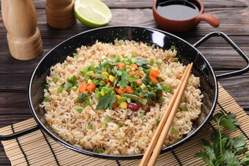 Tasty fried rice with vegetables served on wooden table, closeup