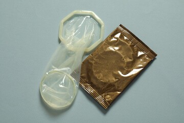 Unrolled female condom and package on light blue background, above view. Safe sex