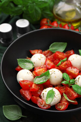 Tasty salad Caprese with tomatoes, mozzarella balls and basil on table, closeup