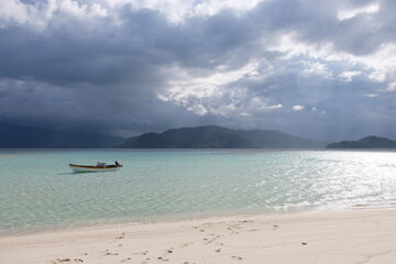 Solo motorboat in beautiful shallow tropical water with rain storm in the distance on a remote island in Papua New Guinea