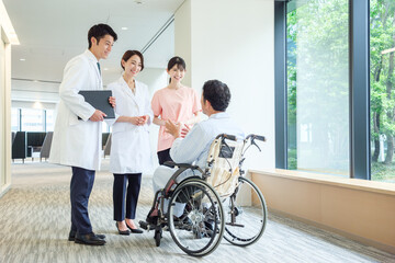 車椅子に乗った男性の患者と会話をする医師