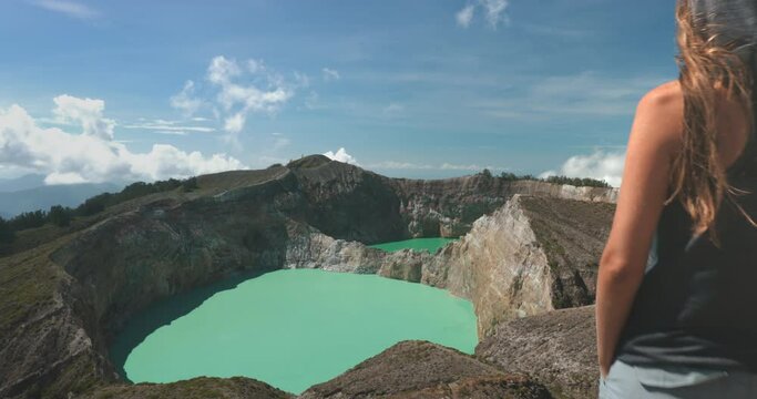Tourist woman enjoy morning view on volcanic Kelimutu blue crater lakes. Nature background. Travel destination. Beautiful wild landscape. Exotic summer vacation, hiking, relax. Close up back view 4K