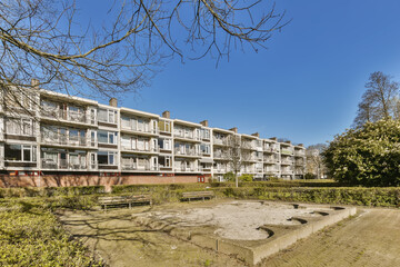 an apartment complex with trees and bushes in the foreground area on a clear blue sky day - stock photo