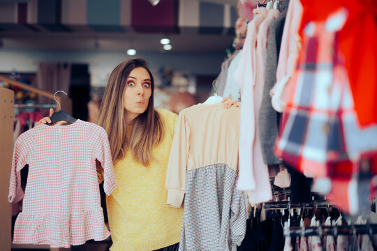 Funny Mom Choosing Between Two Dresses for her little Girl. Undecided shopper thinking which ferment to buy
