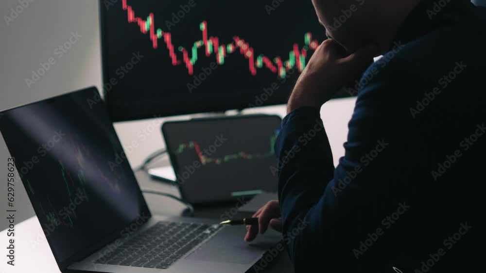Poster Back view of stock market broker in analyzing data and graphs on multiple computer screens while sitting in modern office.