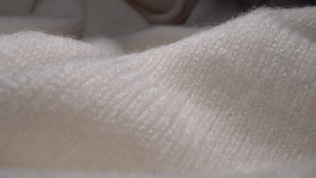 Cozy sheep wool white colored fabric texture in macro. Handcraft knitting woolen sweater. Soft textile abstract background. Winter fashion clothing industry. Home comfort and coziness