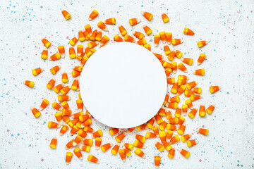 Composition with tasty Halloween candy corns and blank card on light background