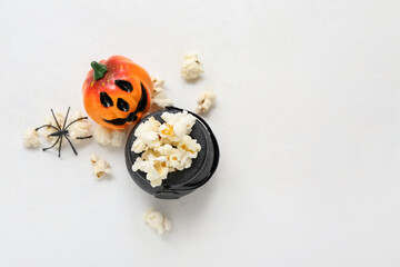 Fototapeta na wymiar Bowl with tasty popcorn, pumpkin and spider on white background. Halloween celebration