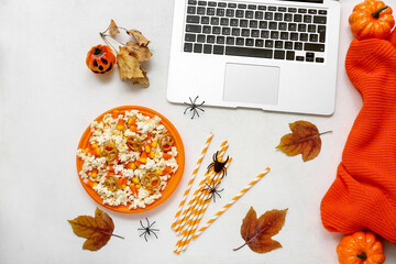 Composition with tasty popcorn, laptop and sweater on white background. Halloween celebration