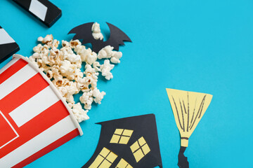 Composition with tasty popcorn and paper decor on blue background, closeup. Halloween celebration