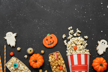 Composition with tasty popcorn, cookies and pumpkins on dark background. Halloween celebration