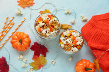 Composition with tasty popcorn, candy corns, pretzels and sweater on white background. Halloween celebration
