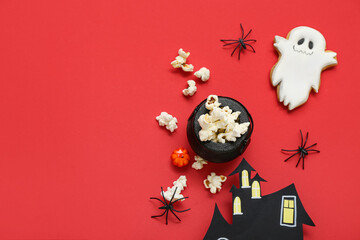 Composition with tasty popcorn, cookie and paper house on red background. Halloween celebration