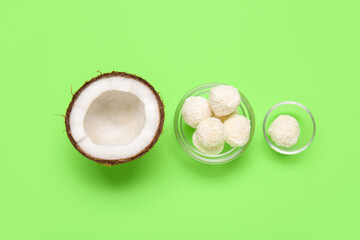 Coconut and bowl with white chocolate candies on green background