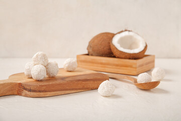 Wooden board with delicious coconut candies on white table