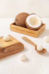 Fototapeta na wymiar Wooden board and spoon with delicious coconut candies on white table