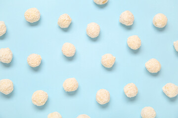 Many white chocolate candies with coconut topping on blue background