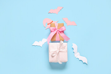 Composition with beautiful gift boxes and Halloween decor on blue background