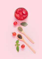 Composition with bowl of canned tomatoes and spices on pink background