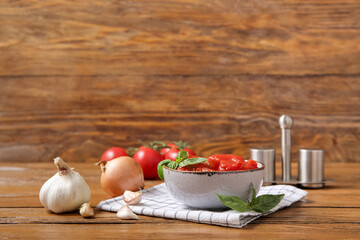 Bowl of canned tomatoes and spices on wooden background