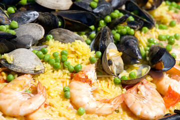 Close up on clams, muscles, shrimp rice and peas cooking in a giant outdoor wok. Mexican seafood dish called Paella