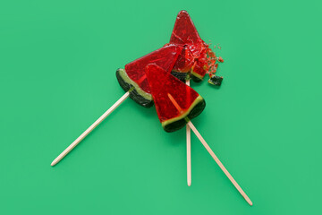 Lollipops in shape of watermelon slice on green background