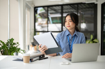 Fototapeta na wymiar A beautiful Asian businesswoman is working on her business tasks at her desk.