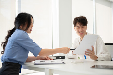 Two professional Asian office workers are discussing work, planning a project together.