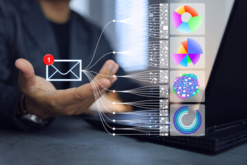 Businessman sitting in office and using laptop computer receiving email containing business data...