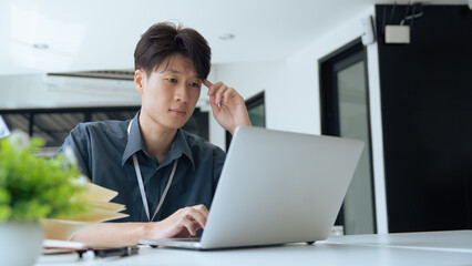 Tired stressed office worker sitting at desk and thinking, he is rubbing his eyes and feeling exhausted