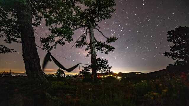 Starry Night Sky Over Mount Olympos In Cyprus With Traveler And Hammock In Silhouette. timelapse