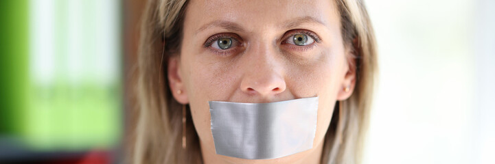 Woman face with adhesive tape covering mouth.