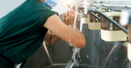 Young female doctor washing hands before operation
