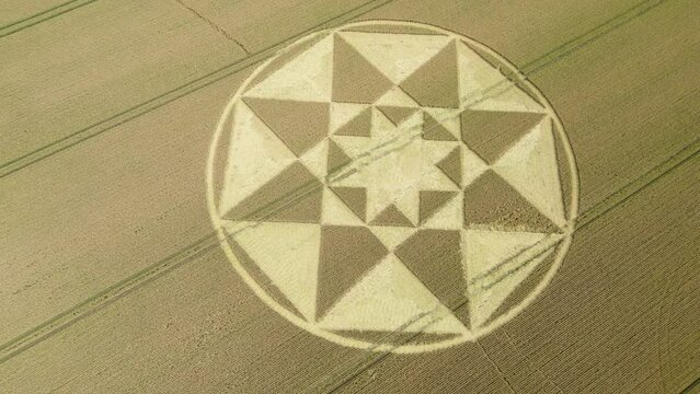 Star shaped crop circle pattern on golden Micheldever wheat field aerial view, Slowly flying above, 2023
