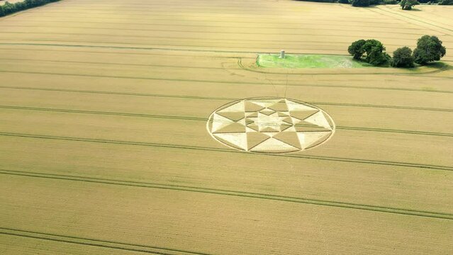 Aerial view circling towards Micheldever geometric star crop circle on Hampshire golden wheat field 2023