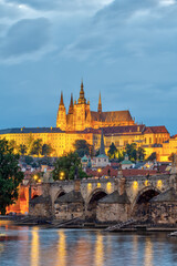 The St. Vitus cathedral with the castle in Prague at night towering above the river Vltava with the famous Charles Bridge - 629784673