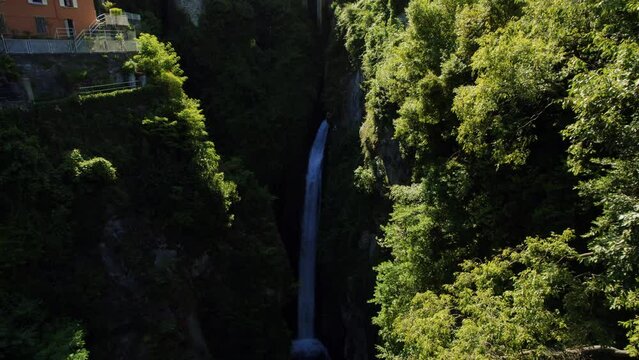 Waterfall in Nesso, Italy, at the end of a Canyon. The Gorge is covered by moss and plants, and the majestic waterfall at the back falls into the river heading to the lake