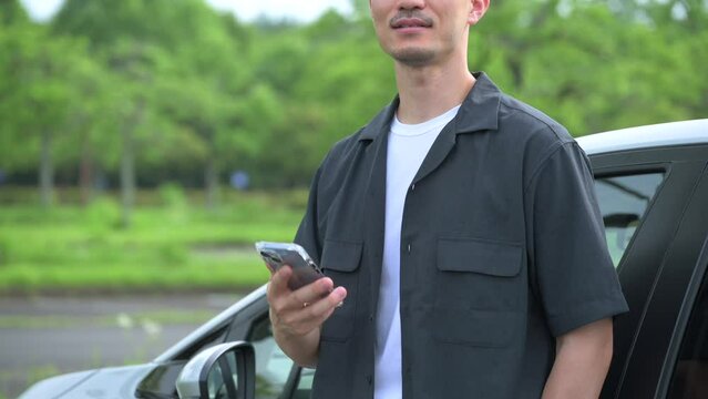A man operating a smartphone next to a car