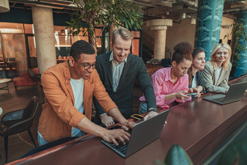 Friendly diverse business people laughing working on project together in modern coworking