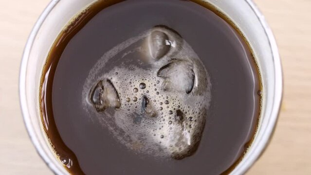 Black coffee with little ice spinning in the glass. top view shot video