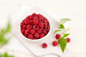 A bowl of fresh raspberries on a white wooden background. Top view.
